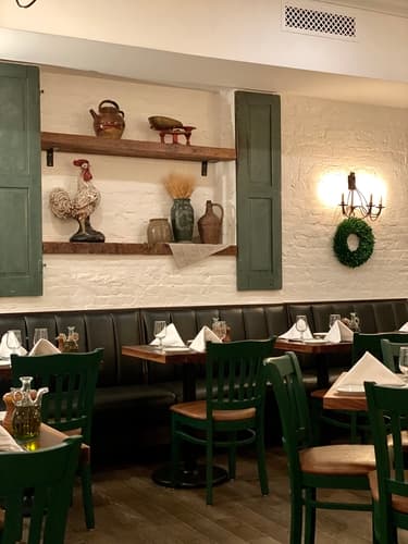 The dining room with a wall shelf, wall sconces and green-trimmed windows