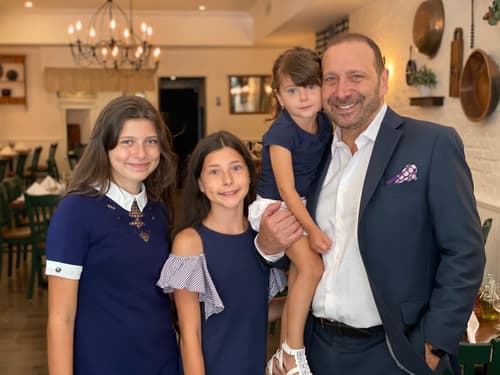 A man standing with three young girls in the dining room