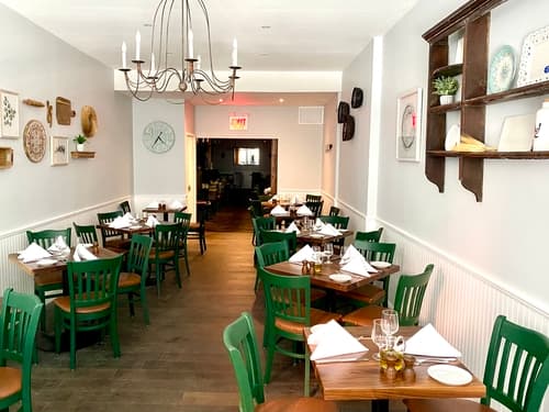 The main dining room with green chairs and wood tables set for dinner