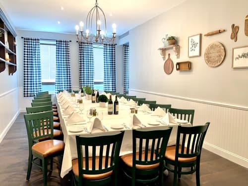 A private dining room with a long table set for a large party and green chairs