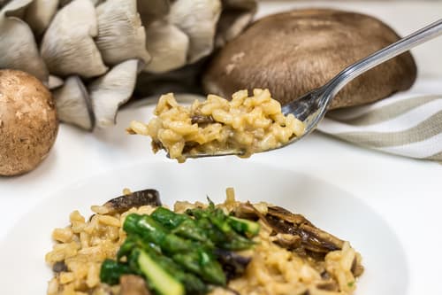Mushroom and asparagus risotto with a forkful lifted from the plate