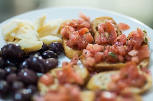 Bruschetta, olives and chunks of cheese on a plate