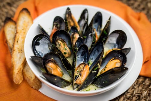 A bowl of mussels in broth with toasted bread