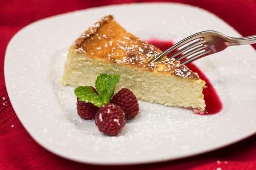 Cheesecake with raspberries and mint on a red berry sauce